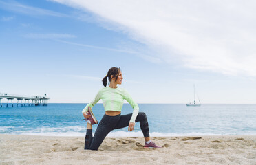 Flexible mature female doing yoga exercises on beach