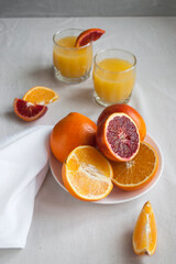 Flat lay of fresh sweet and juicy blood oranges and oranges, whole and cut on a white plate. Fresh orange juice with Sliced oranges.