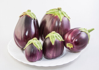 A group of eggplant on a white plate on a white background.