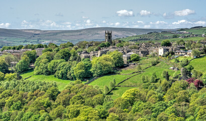 Fototapeta na wymiar the pennine village of heptonstall viewed from across the calder valley with historic church houses and surrounding woodland and steep rocky hills