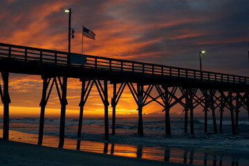 Fototapeta premium American flag flying at sunrise on a pier