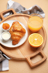 Wooden tray with tasty breakfast on color background