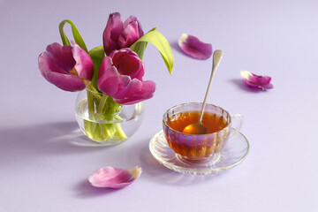 A cup of tea with a bouquet of purple tulips on a pastel background, a side view, a place for text - the concept of a pleasant spring tea party and meetings with friends