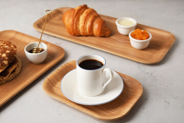 Wooden trays with tasty breakfast on light background