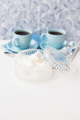 saucer with marshmallows in the background two cups of coffee