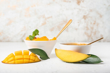 Bowls with mango sauce and fruit salad on light background