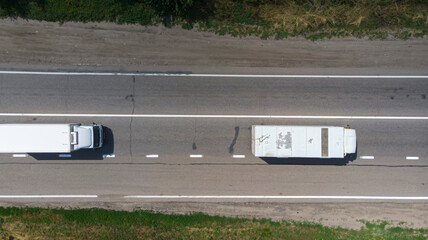 Aerial. Two little trucks driving by the highway. Top view from drone.