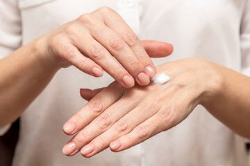 Beautiful female hands moisturize the skin with a cream. Close-up.