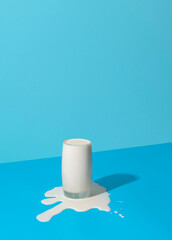 Overflowing glass of milk isolated on a blue background.