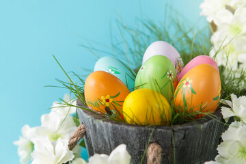 Happy Easter. Colorful Easter eggs and white flower on blue background. Copy space