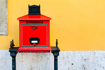 Red old mailbox against a yellow wall in Budapest.