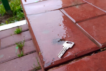 Obraz na płótnie Canvas A flat metal key lies on a red brick porch