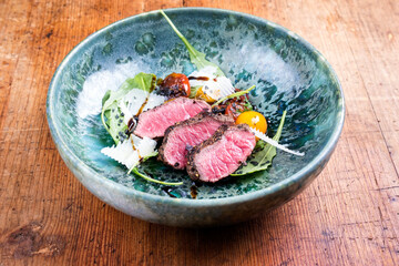 Modern style Italian tagliata di manzo with dry aged sliced sirloin steak and lamb salad served as...