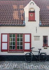 Fototapeta na wymiar maison flamande avec des volets rouges et un vélo garé devant