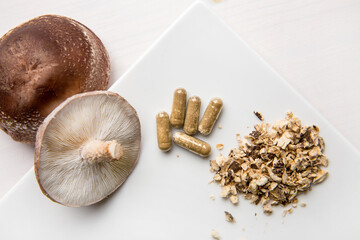 Shiitake Lentinus edoides mushroom supplement capsules with fresh Shiitake mushrooms and powdered...