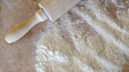 flour and wooden rolling pin on table top view food background