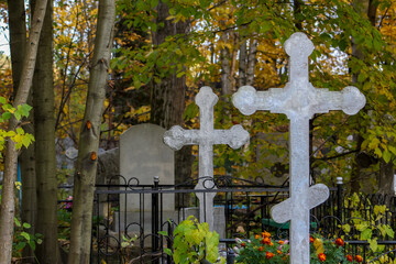 Two silvery grave crosses in the Orthodox Christian cemetery. front view. Autumn graveyard