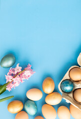 Easter eggs, flowers on blue background. Flat lay, top view, copy space. Easter day.