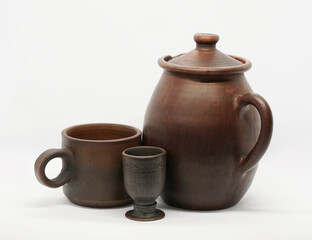 Pottery from a pottery workshop. Ceramic mug for milk, a glass and a jug for brewing meadow herbs (herbalist) on a light background. Russia, Vladimir and Kostroma regions.