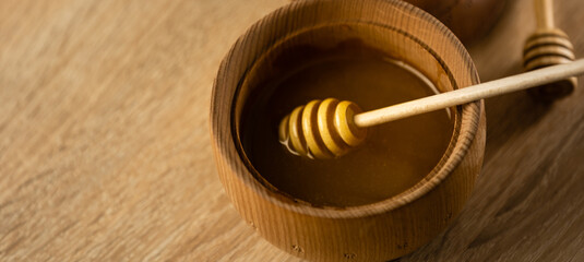 Honey dripping from honey dipper in wooden bowl. Close-up. Healthy organic. Thick honey dipping from the wooden honey spoon, closeup