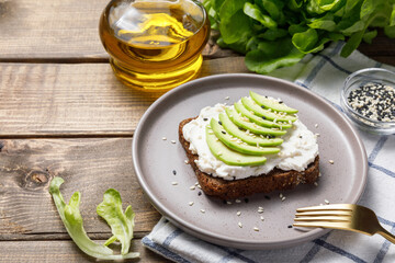 Rye bread toast with avocado and cream cheese on wooden table background. Close up, copy space