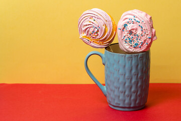 two meringues in a blue mug on a colored yellow-red background