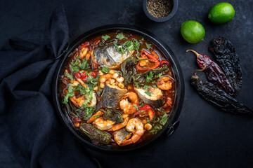 Modern style traditional Mexican seafood pozole soup with fish, king prawns and hominy in a clear...