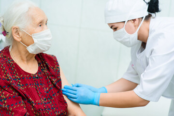a doctor or nurse injects a drug or vaccine into an elderly woman's shoulder. Vaccination against covid-19, diabetes, insulin.