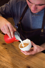 Barista pouring milk in coffee cup for make latte art.