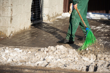 A close-up view as a worker sweeps the pavement out of loose snow
