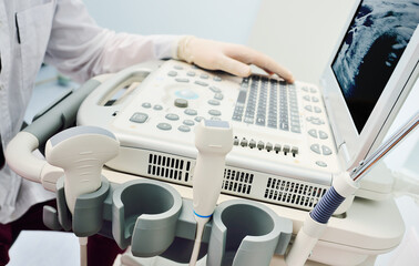 doctor's hands in medical gloves close-up against the background of a modern ultrasound machine in a diagnostic clinic.