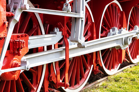 The big red wheels of an old locomotive from the 20th century are photographed in the locomotive museum of an industrial city