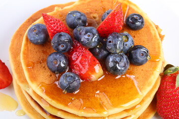 Still life with pancakes, berries and honey on a white background