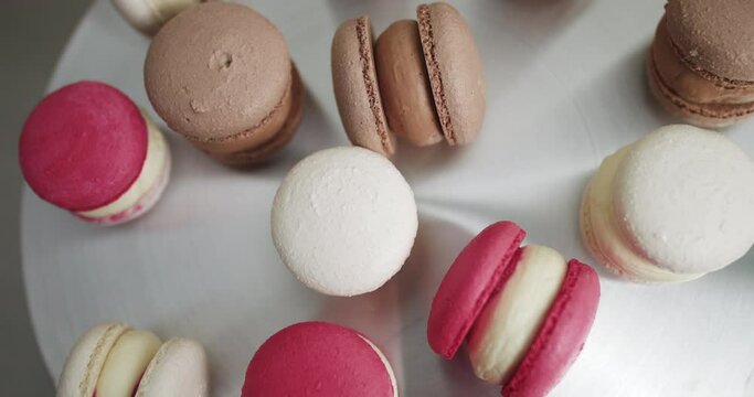 Close up of colorful white, red, and caramel chocolate macarons dessert, filling with tasty ganache, on the table at light kitchen or confectionery shop. Colorful Macarons Colorful Pastel Macarons