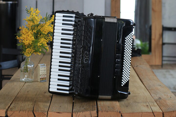 Old beautiful black accordion on a wooden table - obrazy, fototapety, plakaty