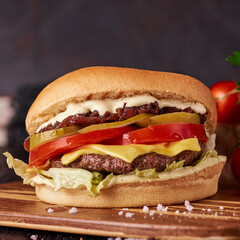 Very delicious and tasty juicy burger or cheeseburger on dark restaurant background. fast food concept banner photo with copyspace.