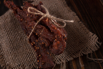 Organic Dried Pork with Pepper Dried Seal, Studio Shot. Jerky on sacking. Wooden background. 