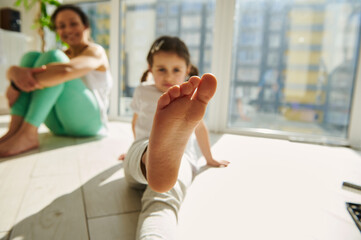 Focus on foot of a little girl exercising with her mom at home