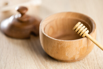 honey in a deep wooden bowl, rustic wooden plate. The wooden spoon drips slowly.