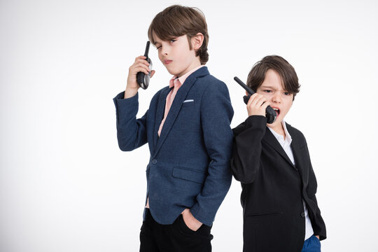 Two young angry managers in suits speaking over portable radio, white background
