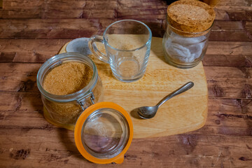 A cup of tea on a wooden chopping board with a brown sugar bowl next to it.