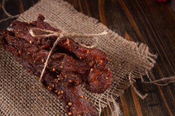 Organic Dried Pork with Pepper Dried Seal, Studio Shot. Jerky on sacking. Wooden background. 