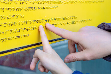 A blind person reads a Braille text and teaches a child how to read it.