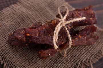 Organic Dried Pork with Pepper Dried Seal, Studio Shot. Jerky on sacking. Wooden background. 
