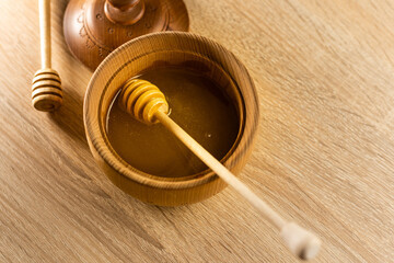 Honey dripping from honey dipper in wooden bowl. Close-up. Healthy organic. Thick honey dipping from the wooden honey spoon, closeup