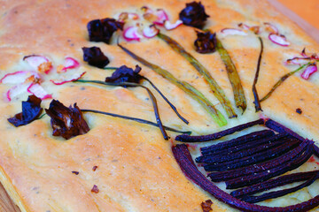 Fototapeta premium View of a focaccia bread decorated with a garden made of vegetables on top