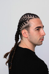 Attractive guy with braids posing in studio on isolated background. Style, trends, fashion concept.