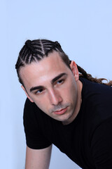 Attractive guy with braids posing in studio on isolated background. Style, trends, fashion concept.