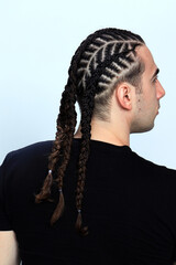 Attractive guy with braids posing in studio on isolated background. Style, trends, fashion concept.