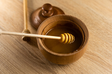 Honey dripping from honey dipper in wooden bowl. Close-up. Healthy organic. Thick honey dipping...